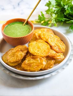 a bowl filled with fried food next to a green dipping sauce