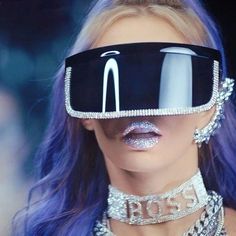 a woman with blue hair wearing a futuristic headpiece and silver jewelry on her face