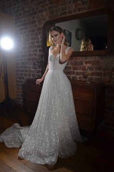 a woman standing in front of a mirror wearing a wedding dress with sequins on it