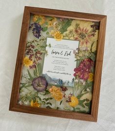 a wooden frame with flowers on it and a wedding card in the bottom right corner