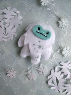 a white stuffed animal sitting on top of snow covered ground next to cut out snowflakes