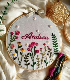 an embroidered name and flowers on a white background with some scissors next to it,