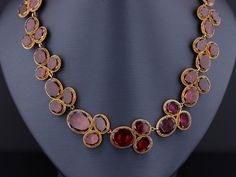 Immerse yourself in the romantic world of high fashion with this garnet riviere necklace. This Georgian piece was designed to please any lady of noble breeding, capturing her heart's desires with every glance. The extraordinary antique necklace (circa 1820) features 54 oval flat-cut garnets, foil and closed backed in 14k bloomed gold. The necklace measures 16 inches and it is in good condition with one surface reaching inclusion that is visible to the naked eye and some past, but well done, repa Luxury Oval Jewelry For Opera, Antique Formal Necklace With Oval Pendant, Antique Oval Pendant Necklace For Formal Occasions, Victorian Oval Jewelry For Opera, Antique Oval Cabochon Gemstone Necklaces, Elegant Garnet Necklace For Formal Occasions, Formal Yellow Gold Garnet Necklaces, Formal Yellow Gold Garnet Necklace, Victorian Ruby Necklace For Formal Occasions