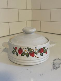 a white casserole dish with strawberries and daisies painted on the side