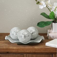 three speckled eggs sitting on a platter next to a vase with flowers in it