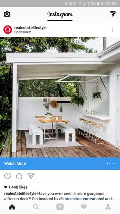 an outdoor dining area with white furniture and wood flooring on a deck overlooking the trees