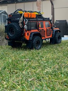 an orange toy truck parked on top of a lush green grass covered field next to a building