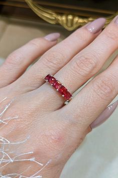 a woman's hand with a ring on it and a red stone in the middle