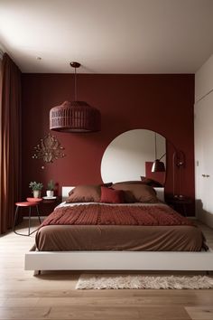 a bedroom with red walls and white bedding in the center is a round mirror on the wall