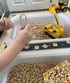 a child is playing with toys in a tray