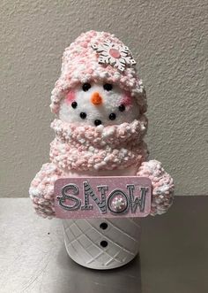 a crocheted snowman sitting in a cup with a name tag on it