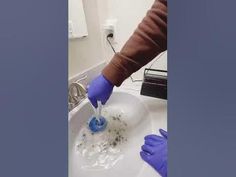 a person in blue gloves is washing their hands