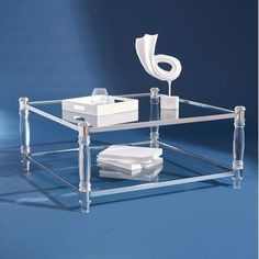 a clear glass coffee table with a white object on it's top and bottom shelf