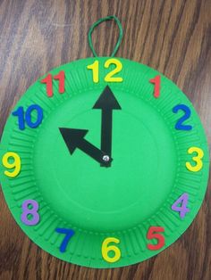 a green paper plate with numbers and an arrow painted on the side, sitting on a wooden table