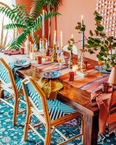 a wooden table topped with lots of candles next to potted plants and greenery