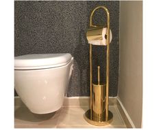 a gold toilet brush holder next to a white toilet in a gray and black bathroom