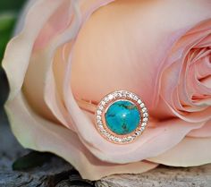 a close up of a flower with a ring on it's end and a rose in the background