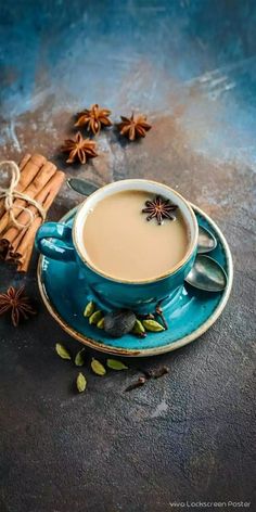 a cup of coffee and cinnamon sticks on a blue saucer with star anise