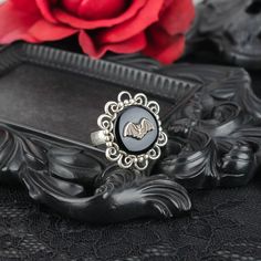 "Add a touch of spooky style to your wardrobe with this vintage style filigree bat ring!  💀 DESCRIPTION: This novelty ring features a small bat stamping that was hand set onto a vintage jet black cabochon and then layered onto an ornate filigree setting. The filigree was mounted onto an adjustable ring base with a simple band. The adjustable overlap is under the base of the ring. 💀 SIZE Adorned portion: 1\" in diameter Band width: 3/16\"  💀 MATERIALS: Cabochon: vintage glass Stamping & setting: oxidized sterling silver plated brass Ring base: antiqued silver plated brass 💀 GIFT: This elegant bat ring comes packaged in a jewelry box, ready for gift giving. If this item is a gift, it can be ship directly to your gift recipient. We'd be happy to include a complimentary gift note. Please l Gothic Silver Ring As A Gift, Gothic Formal Adjustable Rings, Bat Wedding Ring, Adjustable Silver Gothic Rings, Victorian Bat Jewelry, Spooky Birthday, Bat Ring, Bat Jewelry, Gothic Ring