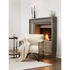 a white chair sitting in front of a fire place next to a table with candles on it