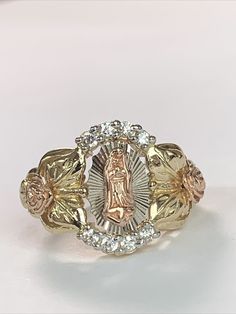 Behold a Religious Christian Ring meticulously crafted from solid 14K yellow and rose gold, accentuated with cubic zirconia that possesses a remarkable brilliance akin to that of diamonds. This ring showcases exceptional stone quality, ensuring a mesmerizing sparkle. The ring boasts a captivating design that seamlessly combines the warmth of rose gold with the radiance of cubic zirconia, resulting in an exquisite piece of jewelry. Craftsmanship of the highest caliber is evident, making it a true work of art. Key Details: Weight: 6.3 grams Size: 7.5 Stamped: Inside, you'll find the unmistakable 14K hallmark, a testament to its genuine and solid gold composition. This ring is not just a symbol of faith but also a testament to your appreciation for fine craftsmanship and quality materials. We Virgencita Gold Ring, Gold Mexican Rings, Mexican Gold Rings, Xv Rings, Quince Rings Gold, Quinceanera Rings, Quince Rings, Hispanic Jewelry, Gold Rings Women