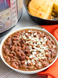 a white bowl filled with beans and onions next to an instant pot