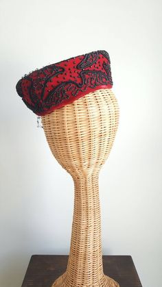 This stunning vintage hat features a striking red silk-velvet base that perches elegantly atop the head; dramatic, faceted black beading; a black net veil and center; and winding ribbon-like corde detailing. Era: 1940s Label: Macy's New York Rise: about 2.75 inches tall 7.5 inches long over top, front to back Elegant Red Ceremonial Headpieces, Evening Headpiece With Tall Crown, Traditional Red Party Hat, Red Evening Hat Headpiece, Net Veil, Formal Cocktail Party, Hourglass Dress, Beaded Hat, Floral Gown