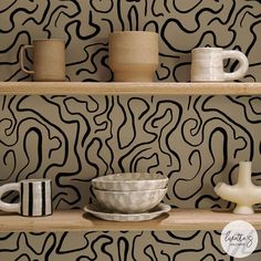 some cups and bowls are sitting on the shelves in front of a wallpapered background