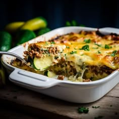 a casserole dish with zucchini and meat in it on a wooden table