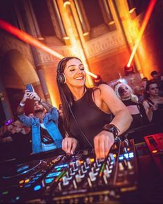 a woman wearing headphones is playing music on a dj's mixer at a party