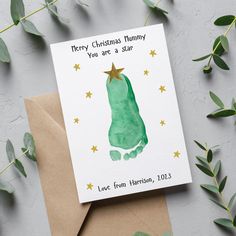 a christmas card with a green handprint on the front and gold stars on the back