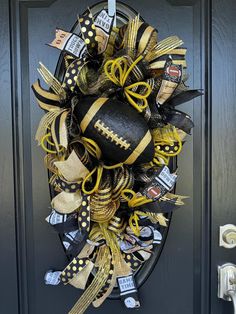 a football wreath with black and gold decorations hanging on the front door to welcome you