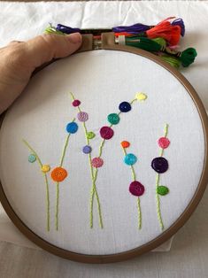 a person holding up a cross stitch project with colorful flowers on the front and side