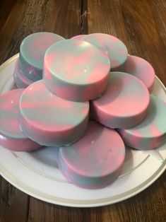 pink and white soaps on a plate sitting on a wooden table