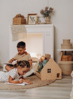 two children are playing on the floor in their living room, one is reading a book