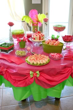 a pink table topped with lots of desserts and candies on top of it