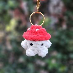 a stuffed animal keychain with a red hat hanging from it's side