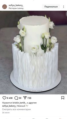 the cake is decorated with white flowers and ruffles