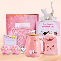 a pink coffee mug with cat magnets on it and other items in front of it