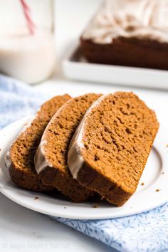 three slices of cake on a plate with frosting and a glass of milk in the background