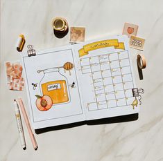 an open planner with honey on it next to other items and pens, pencils and markers