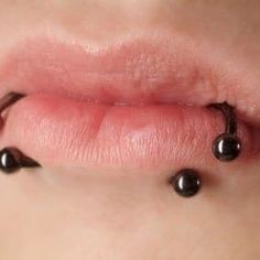 a woman's lip with black balls attached to the end of her tongue and nose