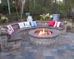 an outdoor fire pit with seating around it and lots of pillows on the seat cushions