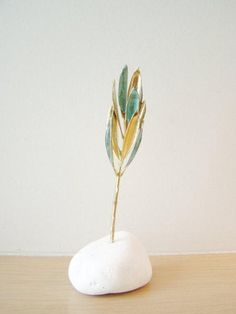 a small white rock with a green plant in it sitting on a wooden table next to a wall