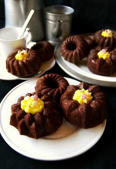 chocolate bundt cakes with yellow icing on white plates next to silver teapots