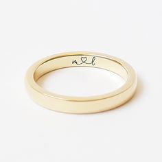 a gold wedding ring with the word love engraved on it's side, against a white background