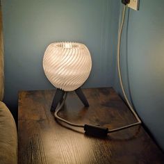 a white lamp sitting on top of a wooden table next to a light plugged in