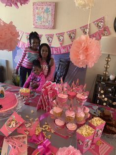 two girls standing in front of a table with cupcakes and cakes on it