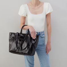 This bag has everything you want in a tote: top zip closure, a padded tech pocket, solid leather straps, and Sheila's signature circular handles that fold down when not in use! Sleek Shoulder Bag With Leather Top Handle, Sleek Top Handle Shoulder Bag With Leather Handles, Sleek Travel Shoulder Bag With Leather Handles, Sleek Shoulder Bag With Detachable Handle For Shopping, Sleek Black Shoulder Bag With Leather Handles, Sleek Daily Bags With Leather Handles, Sleek Shopping Bags With Detachable Handle, Sleek Shopping Bag With Detachable Handle, Black Satchel With Round Handle For Travel