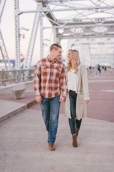 a man and woman walking down the sidewalk together in front of an overpass bridge